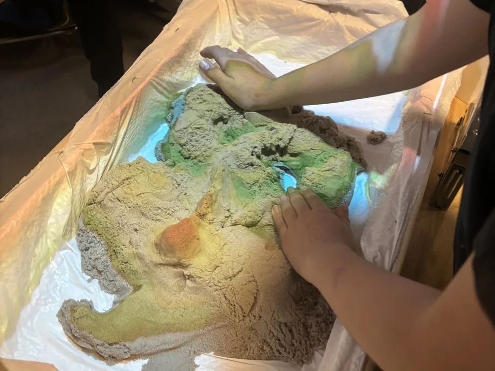 Users actively manipulating sand terrain with real-time AR feedback